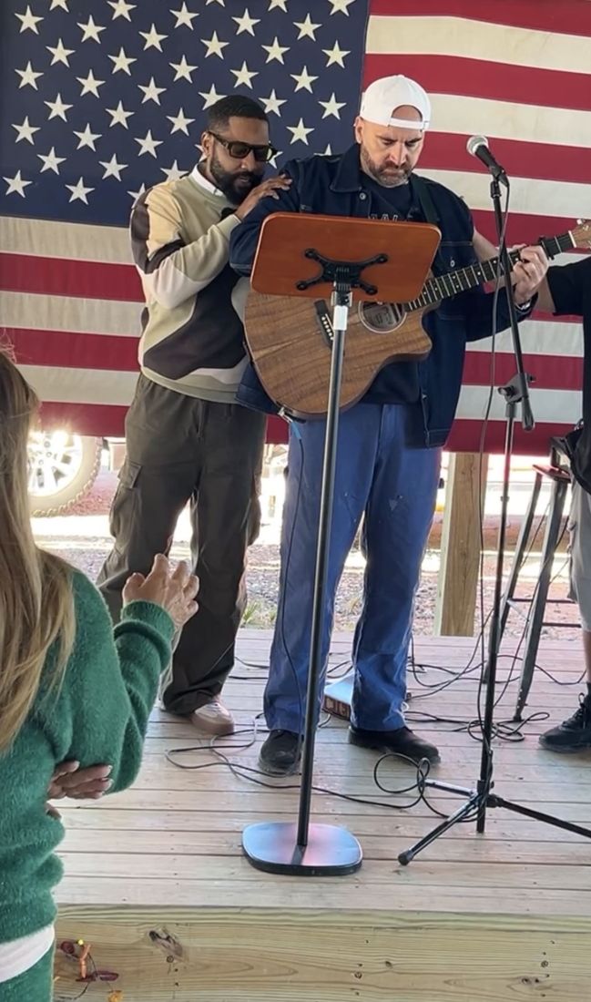 Alabanza con guitarra frente a la bandera de Estados Unidos